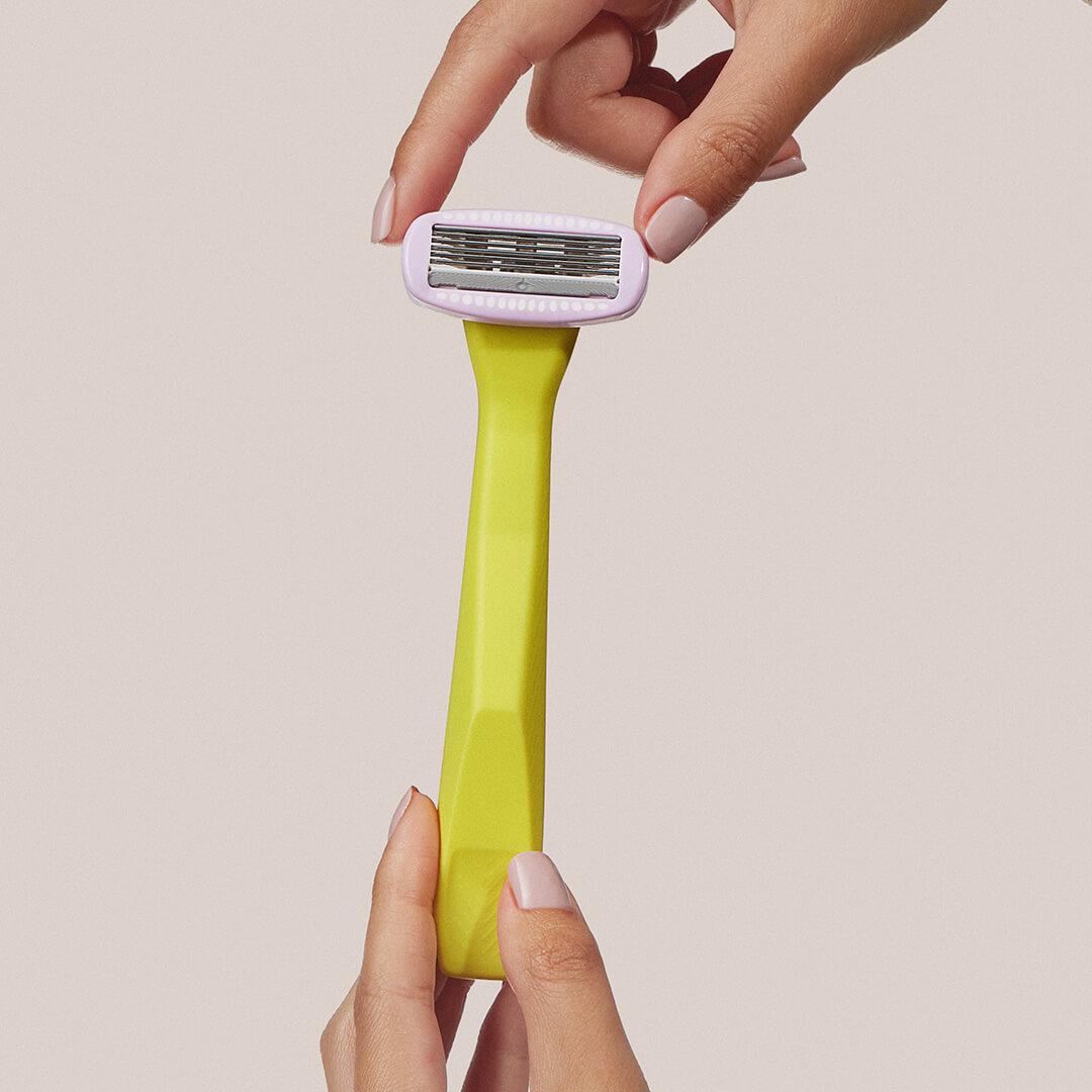 Close-up of a model holding the REFRESHMENTS Dazzling 5-Blade Razor with two hands