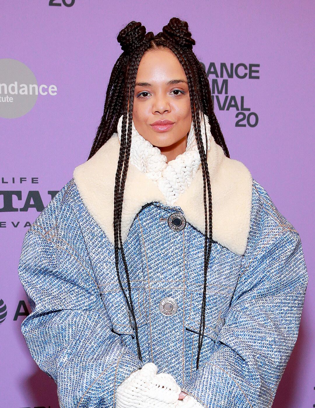 Tessa Thompson wearing a denim winter jacket and rocking a braided hairstyle with space buns