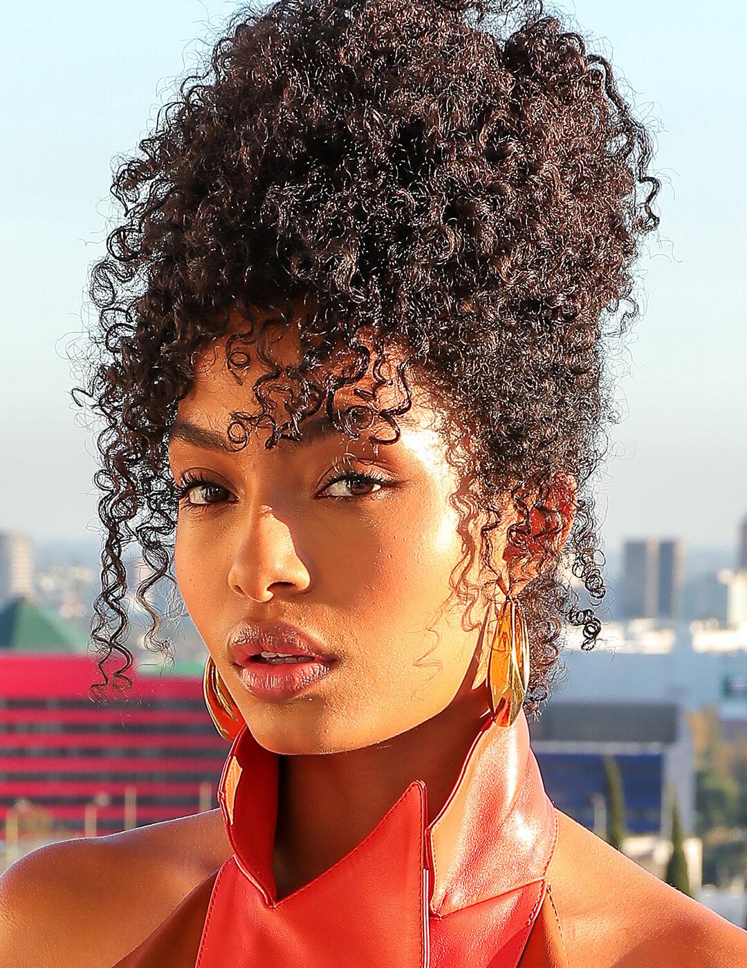 Yara Shahidi rocking a curly updo hairstyle during golden hour