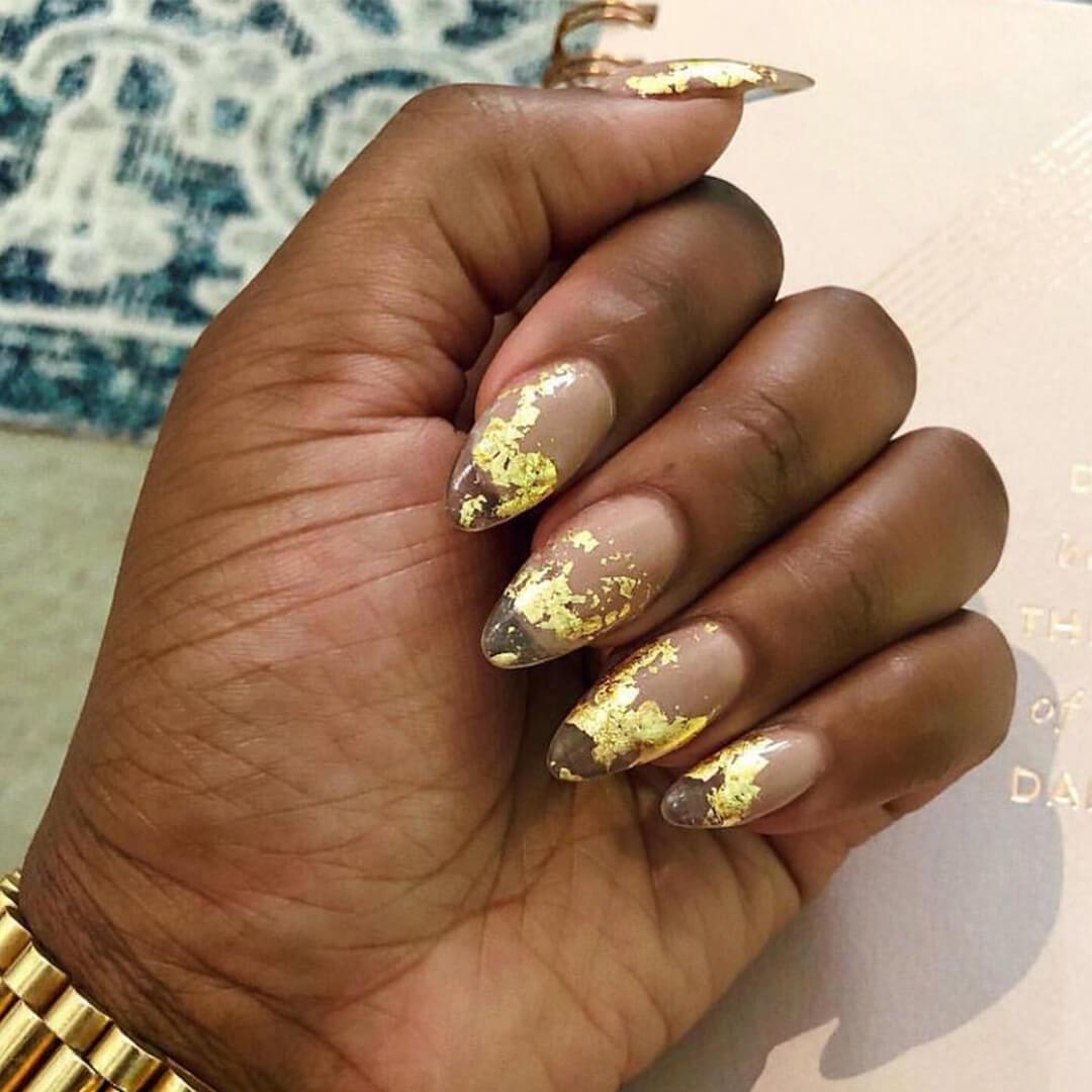 Close-up of a woman's hand with gold foil ombré nail art