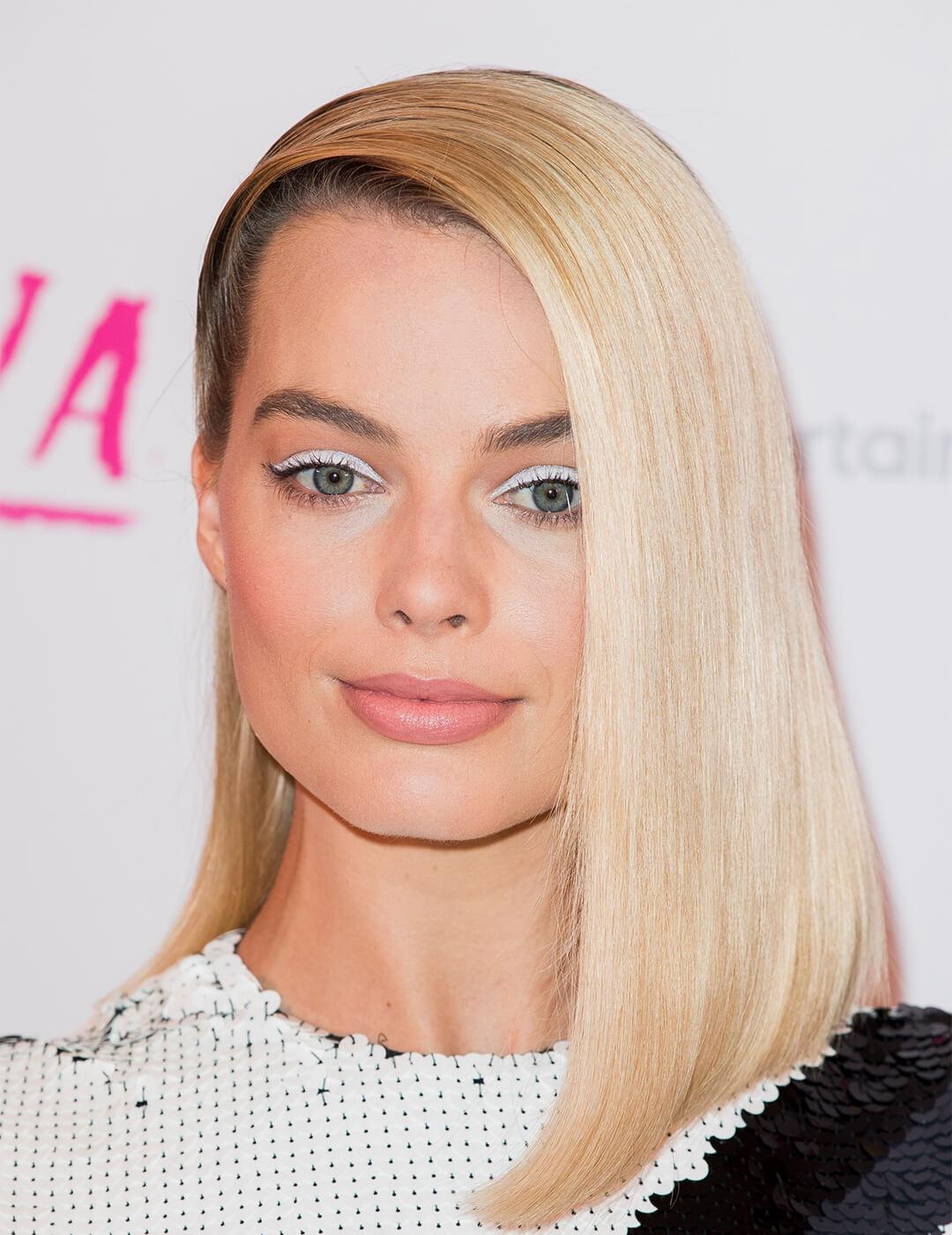 Close-up of Margot Robbie rocking a white eyeshadow makeup look and deep side parted hairstyle