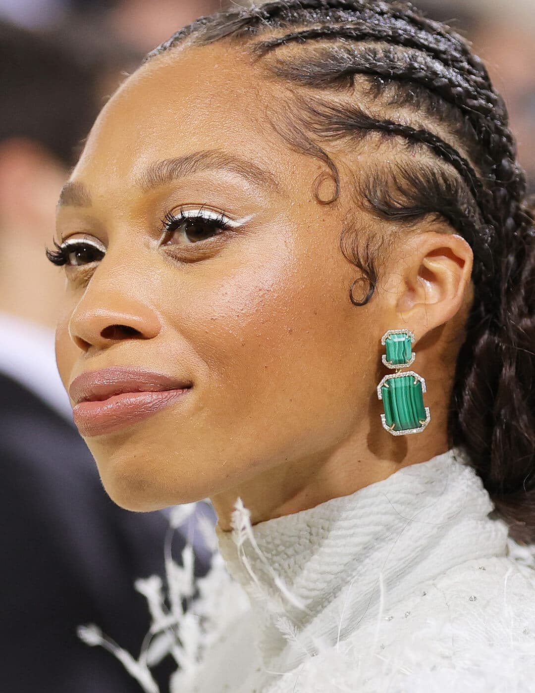 Allyson Felix rocking a white eyeliner makeup look, braided hairstyle, and bold, green earrings