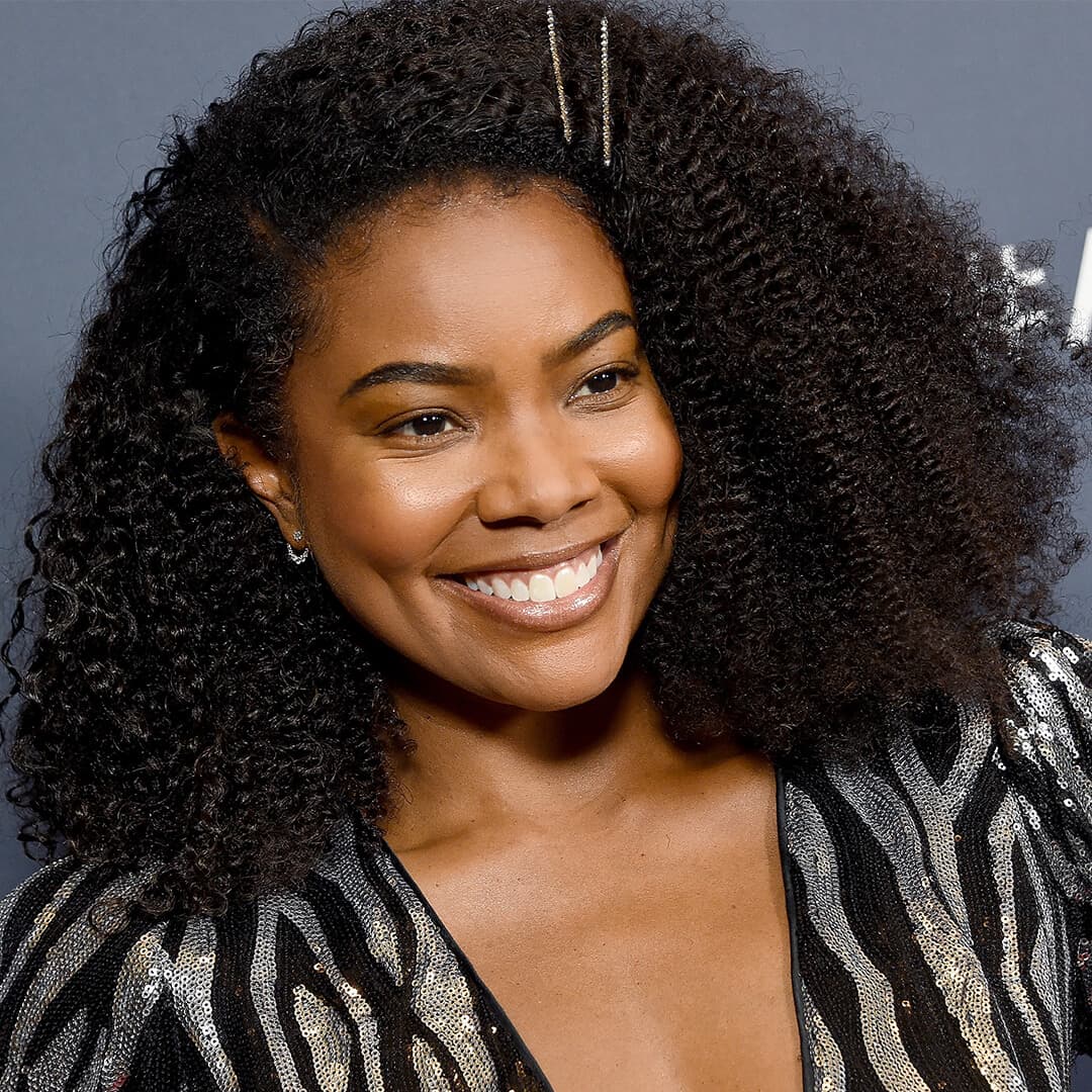 Gabrielle Union in a black and silver sequined dress rocking her pinned back natural curls while smiling