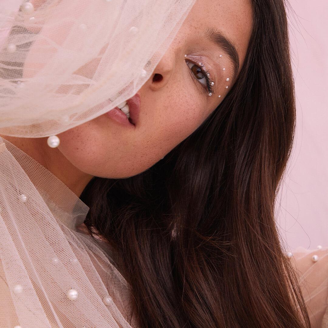 Close-up image of a model hiding behind her lacy outfit