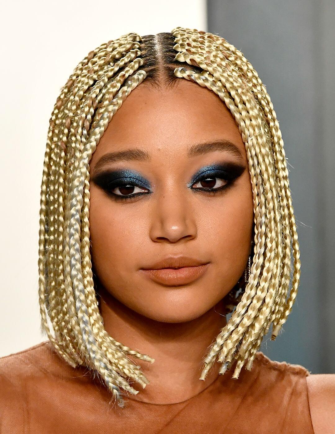 A photo of Amandla Stenberg with gold-colored braided hair and defined smokey eyeshadow