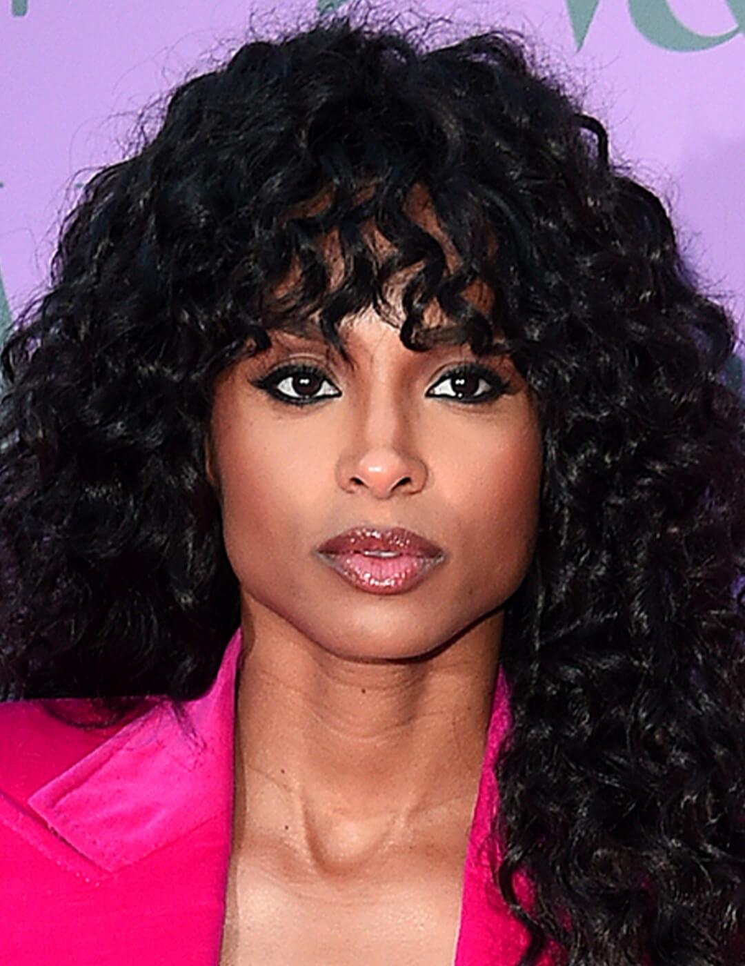 A photo of Ciara with a curly shag wearing a bright pink coat