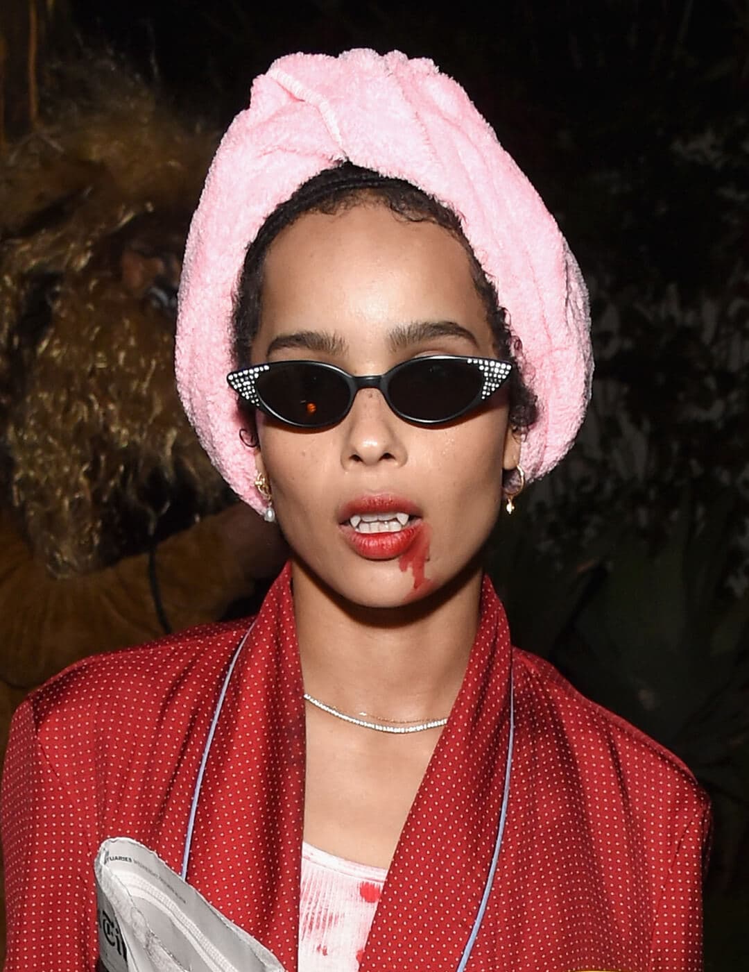 Zoe Kravitz dressed up as a vampire in a red bathrobe, pink headwrap, and cool sunglasses