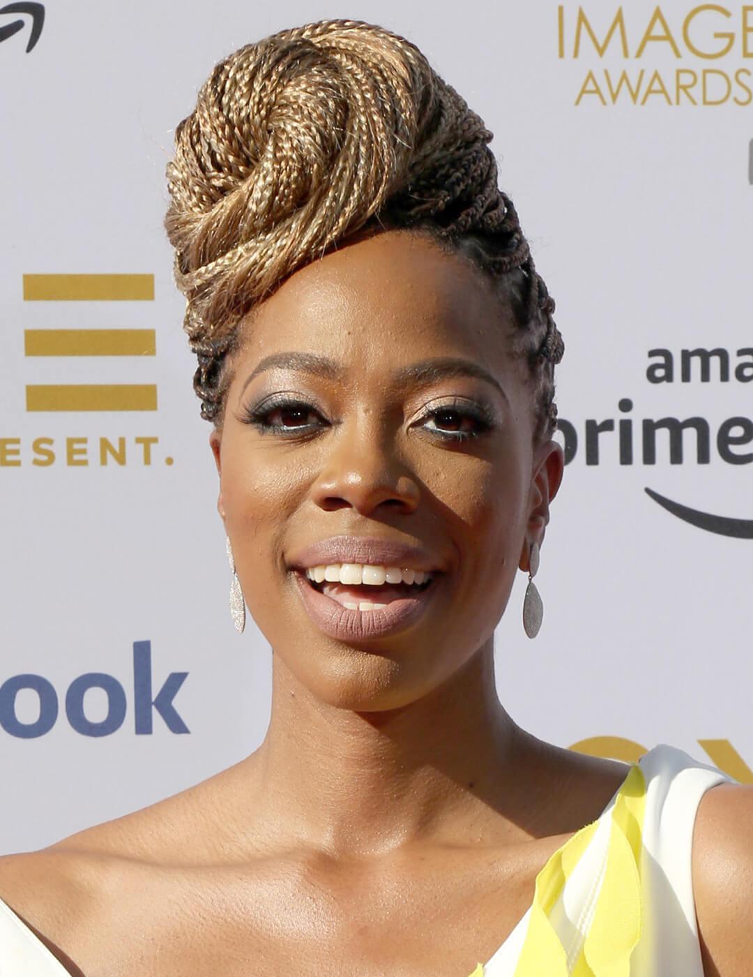Yvonne Orji rocking a yellow and white dress and braided spiral bun hairstyle