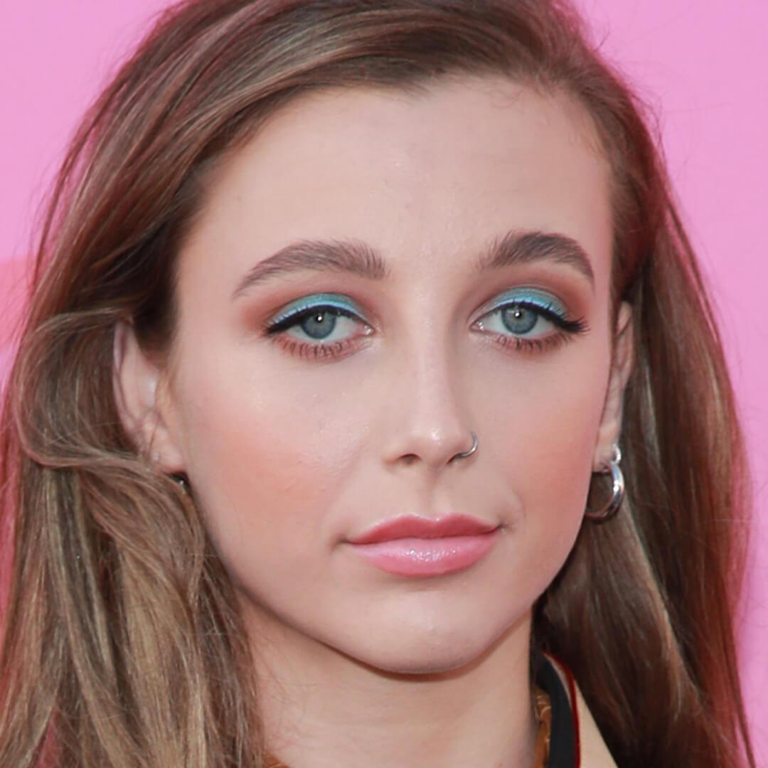 Close-up image of Emma Chamberlain rocking a red and blue-green eyeshadow look paired with a pink lipstick