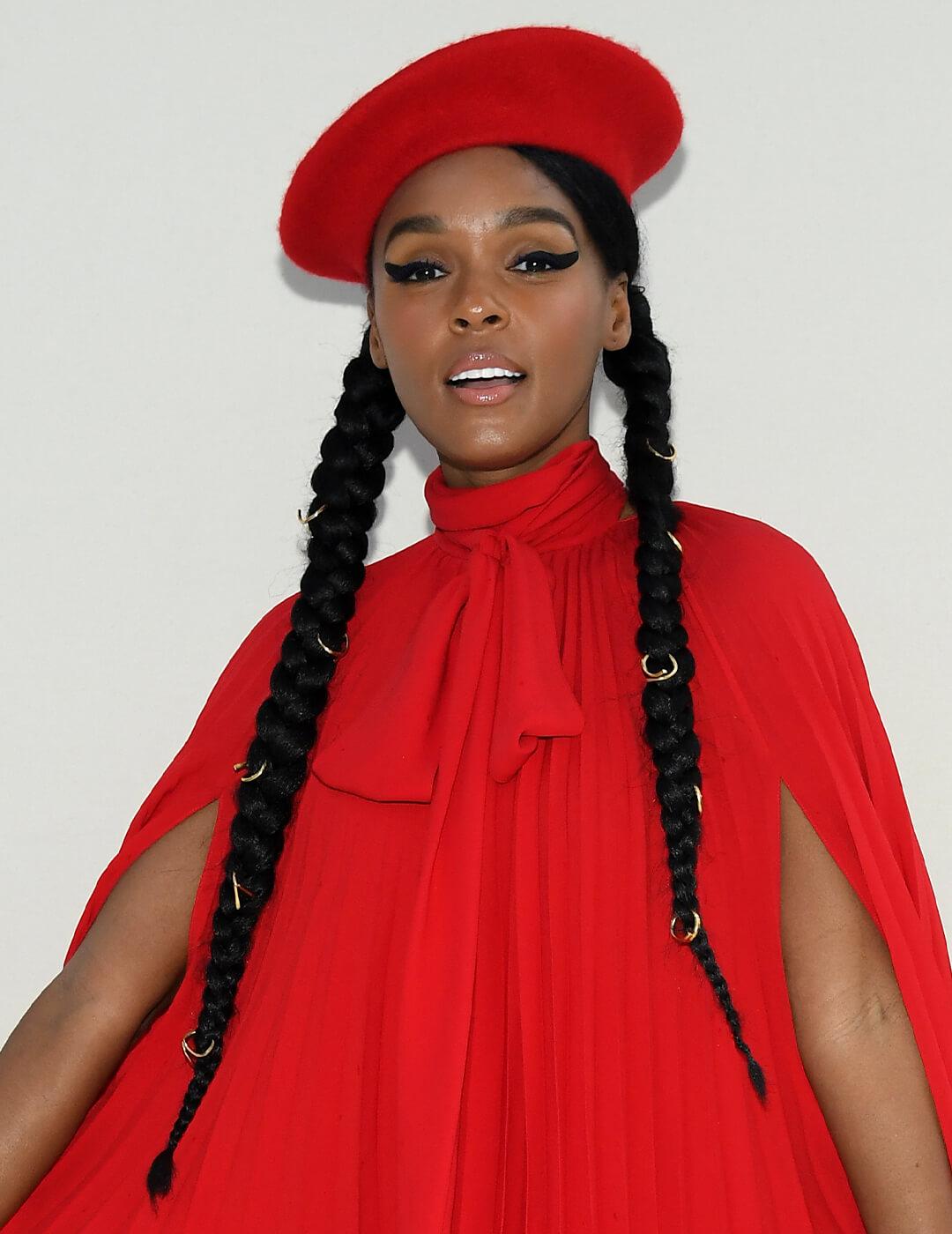 Janelle Monae going bold with a red dress, thick cat eye look, and braided pig tails with gold accents