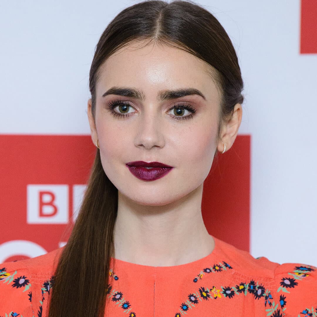 Lily Collins rocking berry lips, soft pink eyeshadow makeup look, and low side ponytail hairstyle