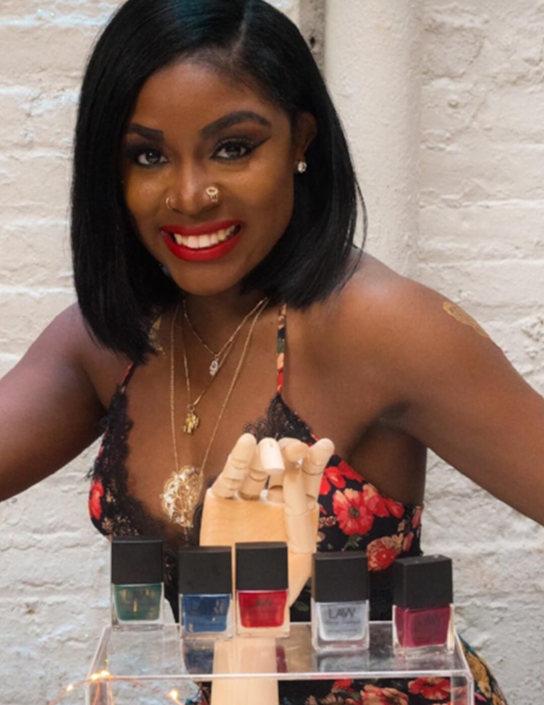 LAW BEAUTY ESSENTIALS founder Tanisha Lawrence posing with nail polishes