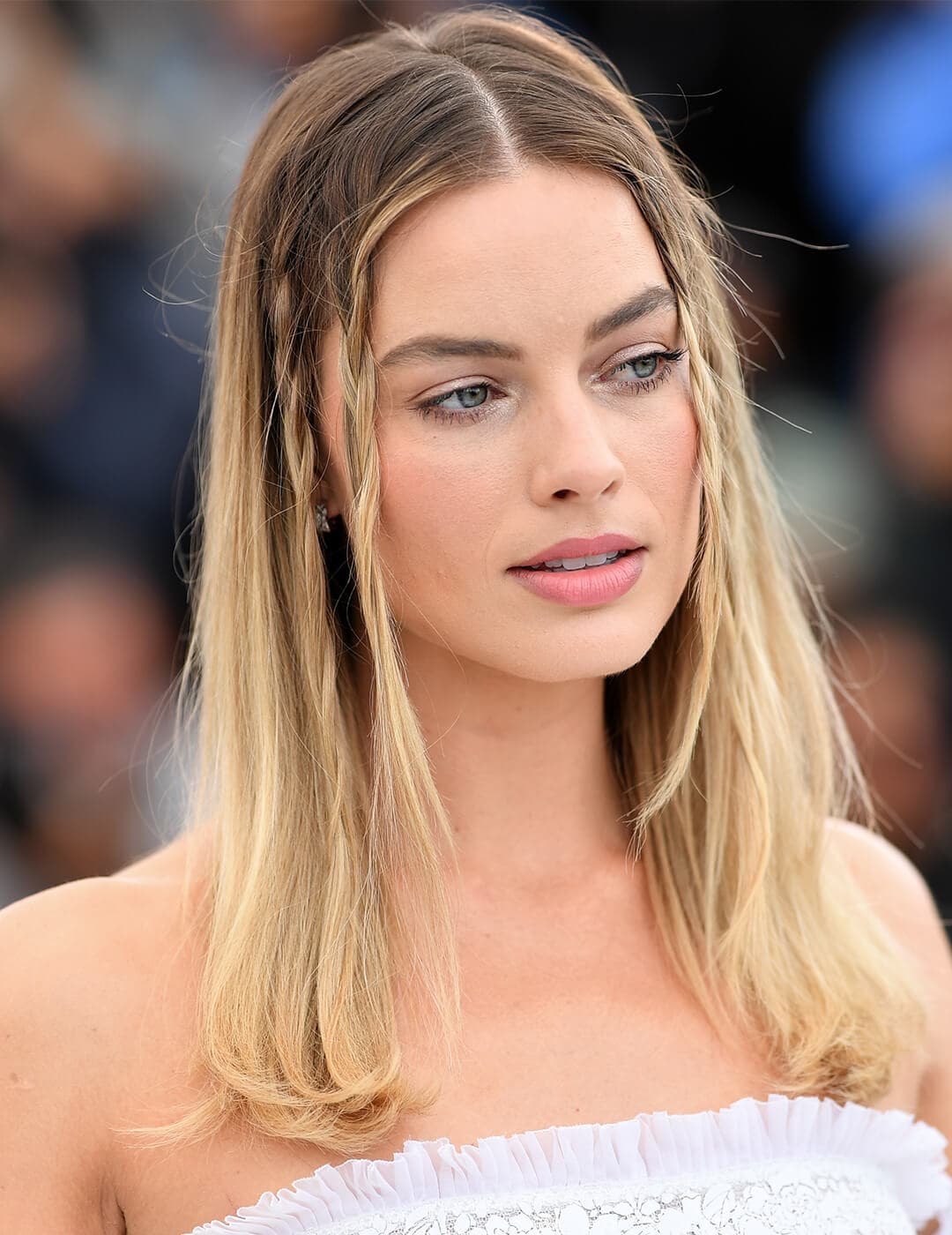 A photo of Margot Robbie with ombre blonde hair and with baby braids wearing a frilly white dress