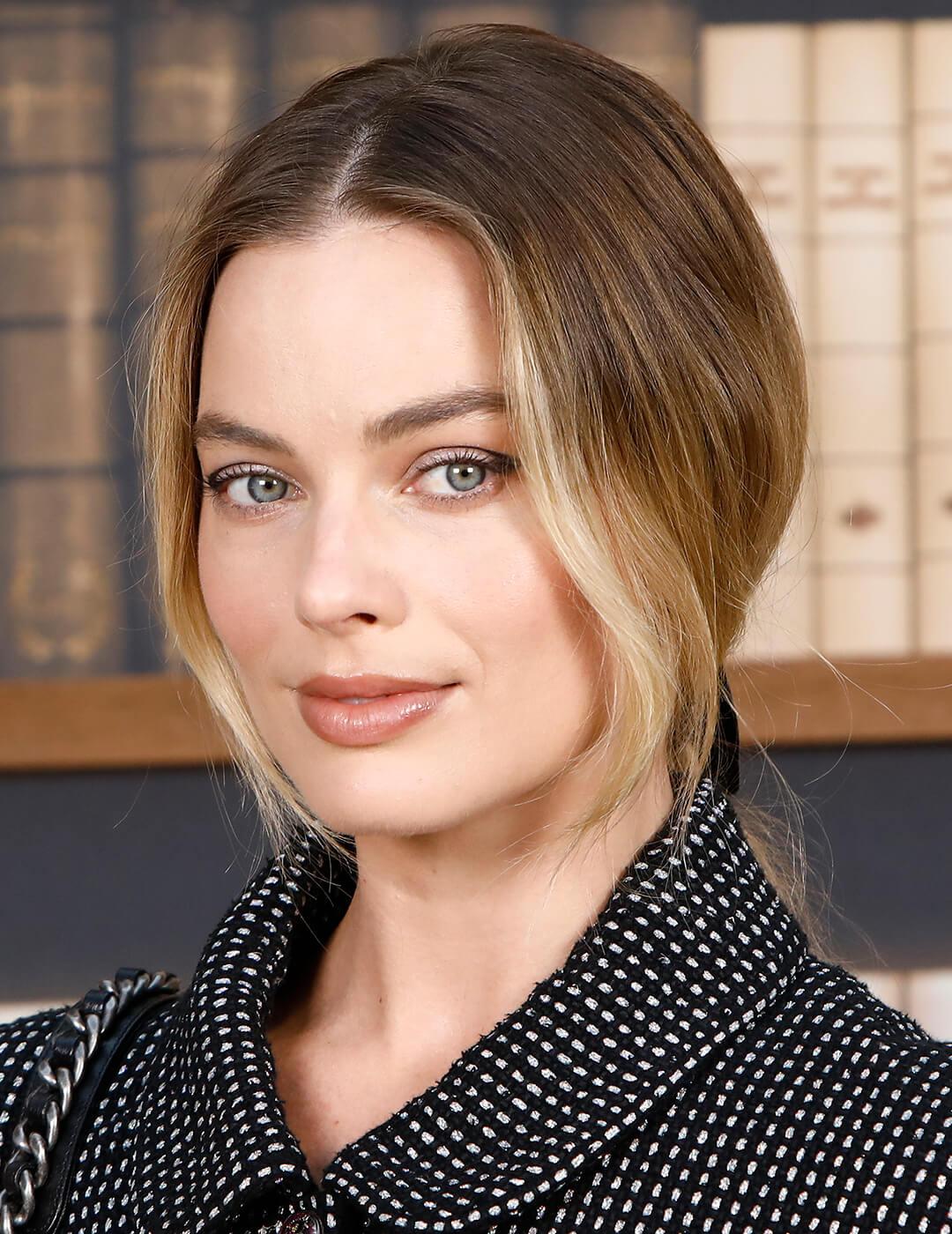 Margot Robbie rocking a black and white tweed coat and low ponytail hairstyle with loose bangs