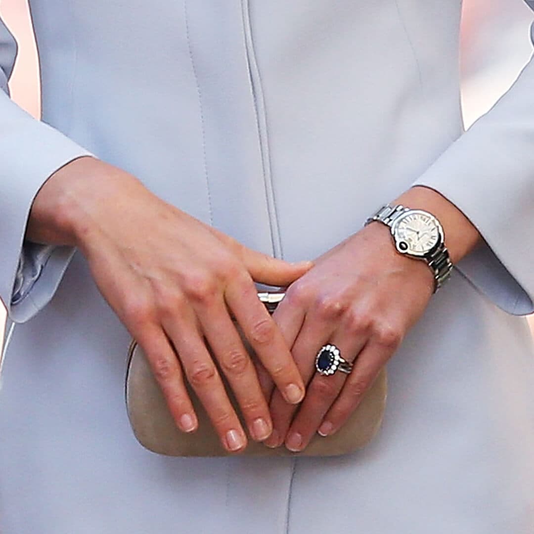 Close-up of Catherine, Duchess of Cambridge's hands with polished bare nails holding a light brown purse