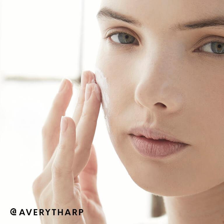 Model Avery Tharp applies foam cleanser on one side of her face