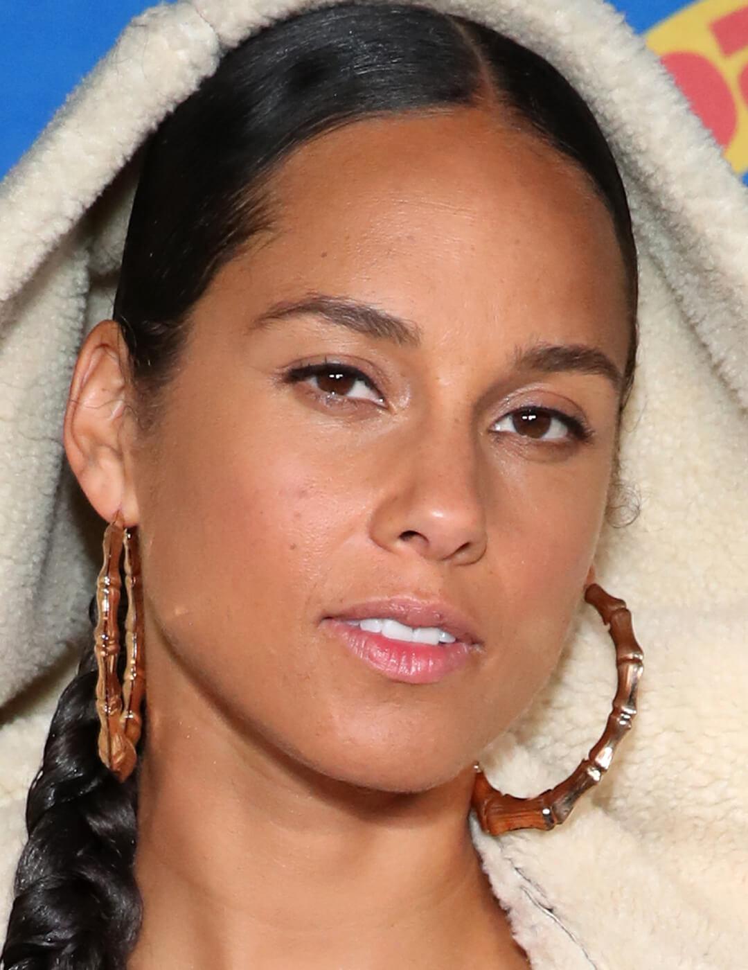 Close-up of Alicia Keys with a no-makeup makeup look and gold hoop earrings