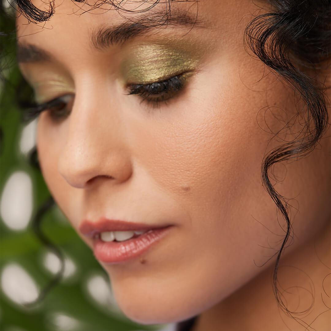 Close-up of a model with a shimmery emerald green eyeshadow makeup look looking down