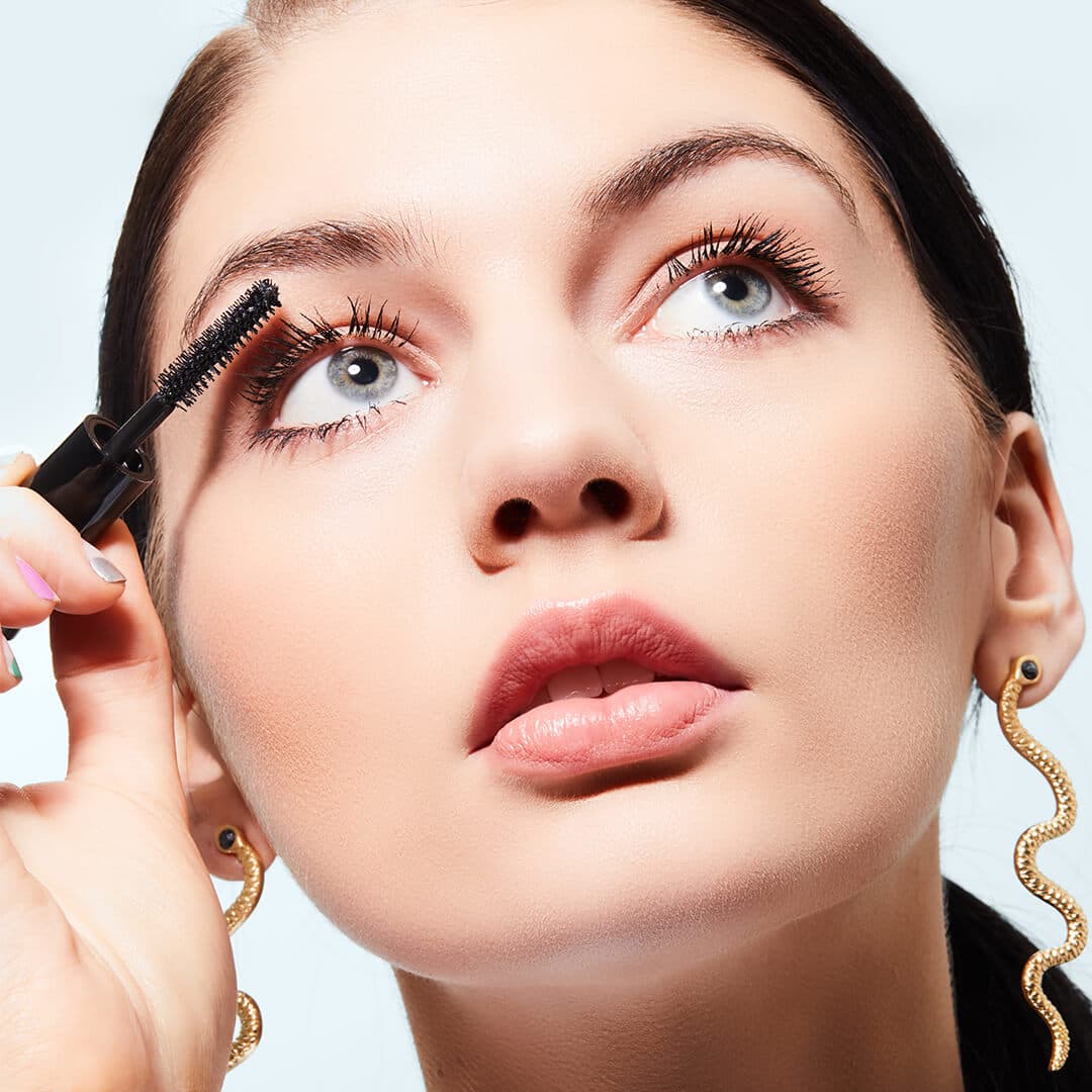 Close-up of a model looking up while applying mascara