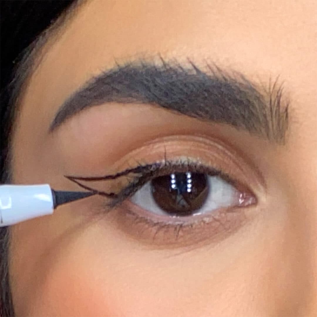 Close-up of a woman connecting her cat eye guide with an eyeliner