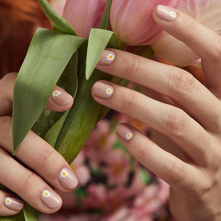 Close-up of a model's hands with white daisies nail art holding tulips