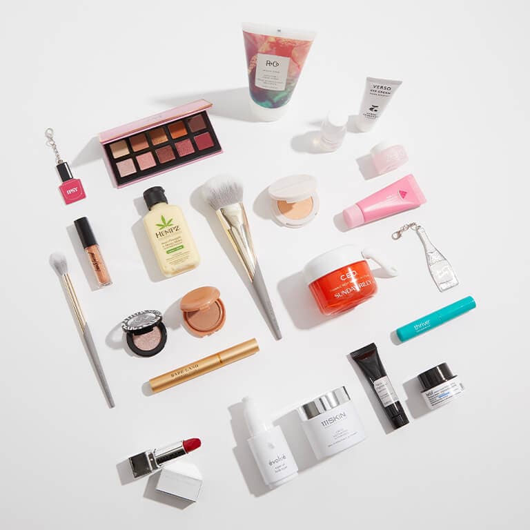 An image of makeup, skincare, and hair care products laid on a white surface