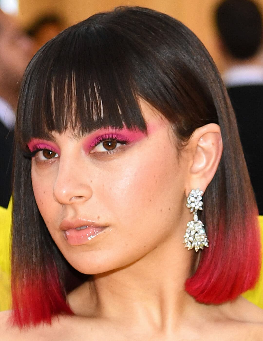 An image of Charli XCX showing her red-dyed tip hair together with her pink, smudgy look eyeliner