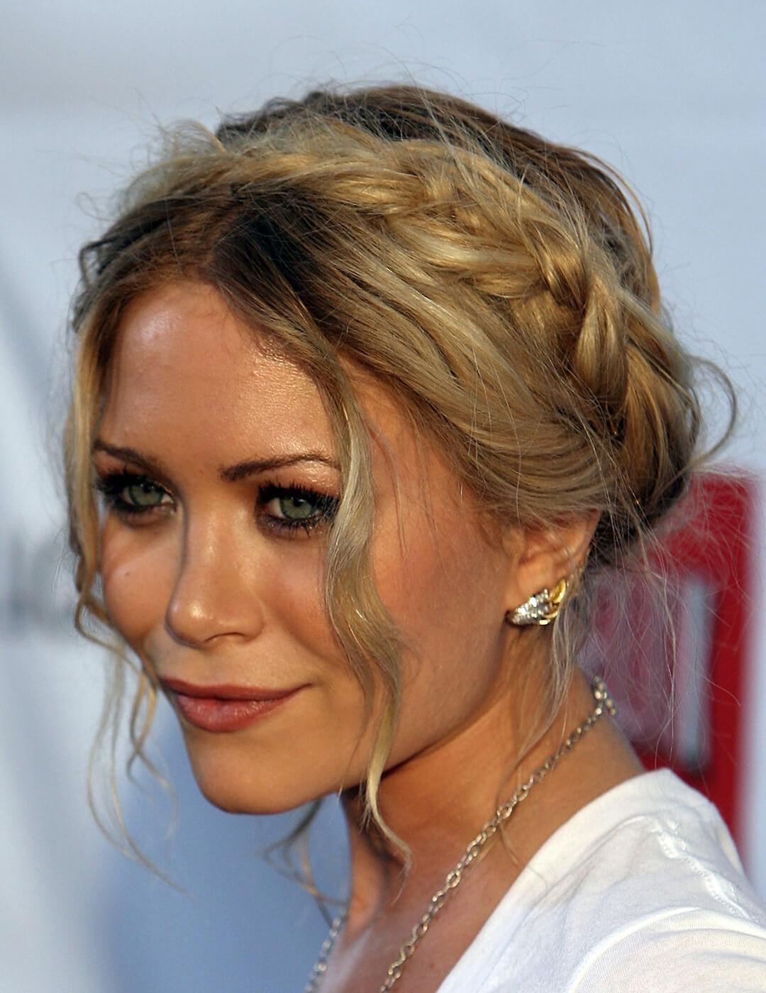 A photo of Mary-Kate Olsen with braided bangs wearing a white shirt and a necklace