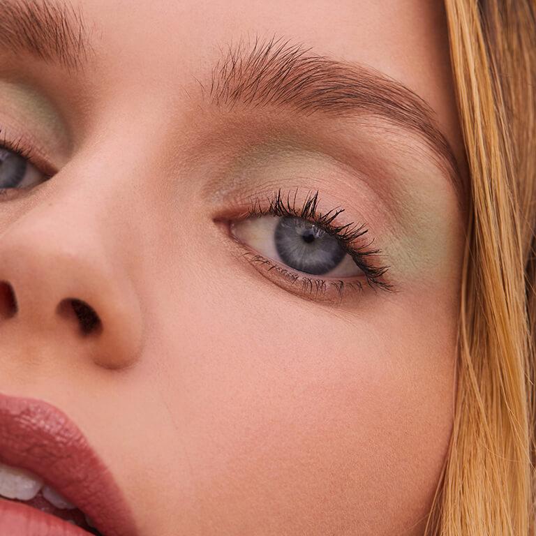 A closeup image of a model wearing nude and mint green eyeshadow