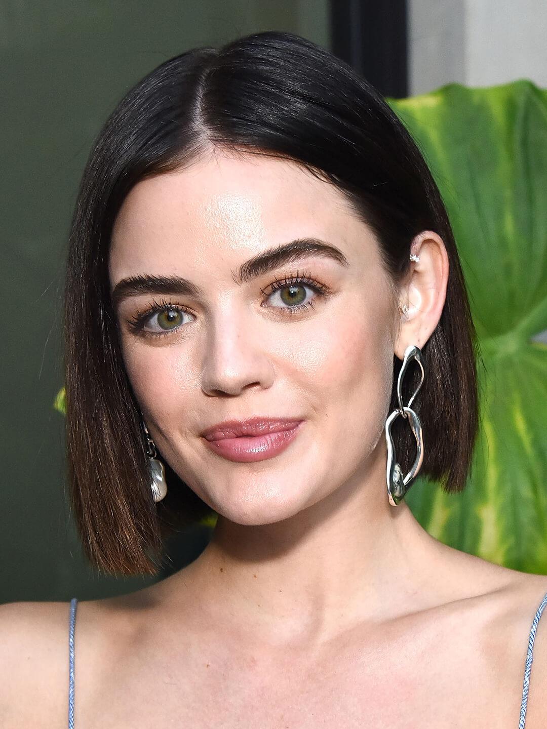 Close-up image of Lucy Hale rocking dangling earrings and a short asymmetrical bob hairstyle