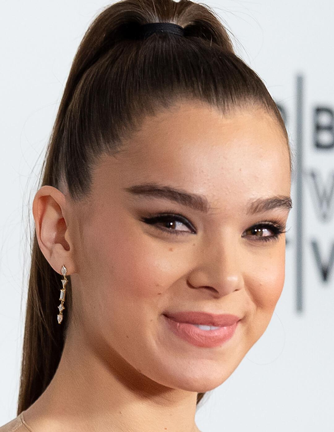 Hailee Steinfeld rocking a high ponytail hairstyle, cat eye makeup look, and nude lips