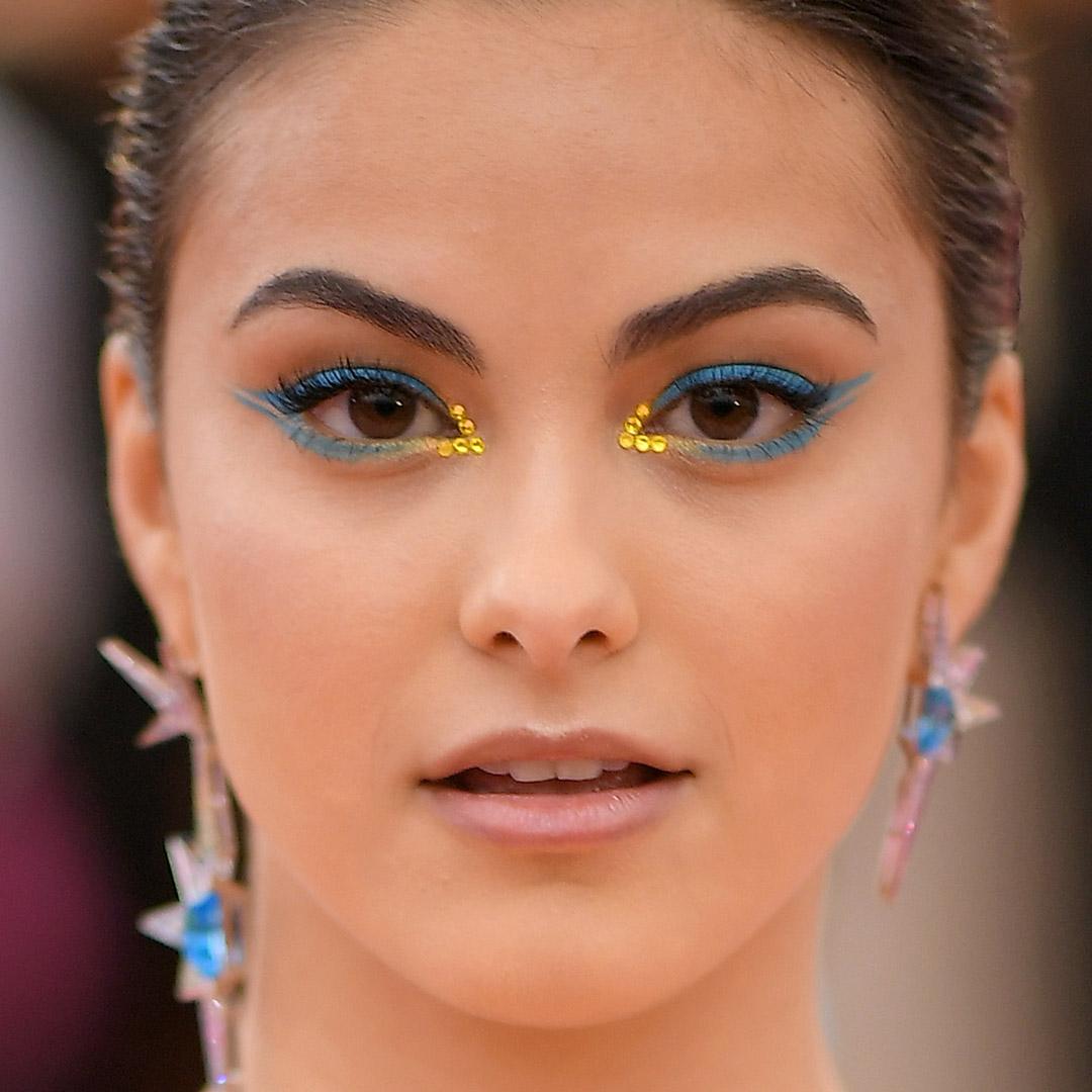 A photo of  Camila Mendes with yellow rhinestones and a turquoise double wing eyeliner