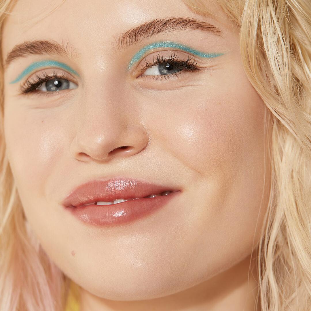 Close-up of a smiling model rocking a green eyeliner makeup look