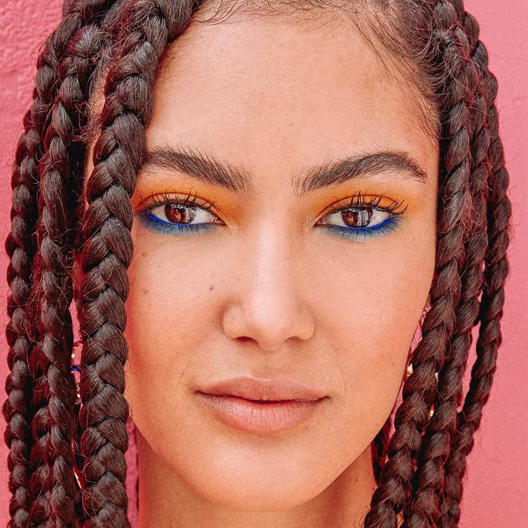 Close-up of a young woman rocking a colorful eye makeup and braided hairstyle