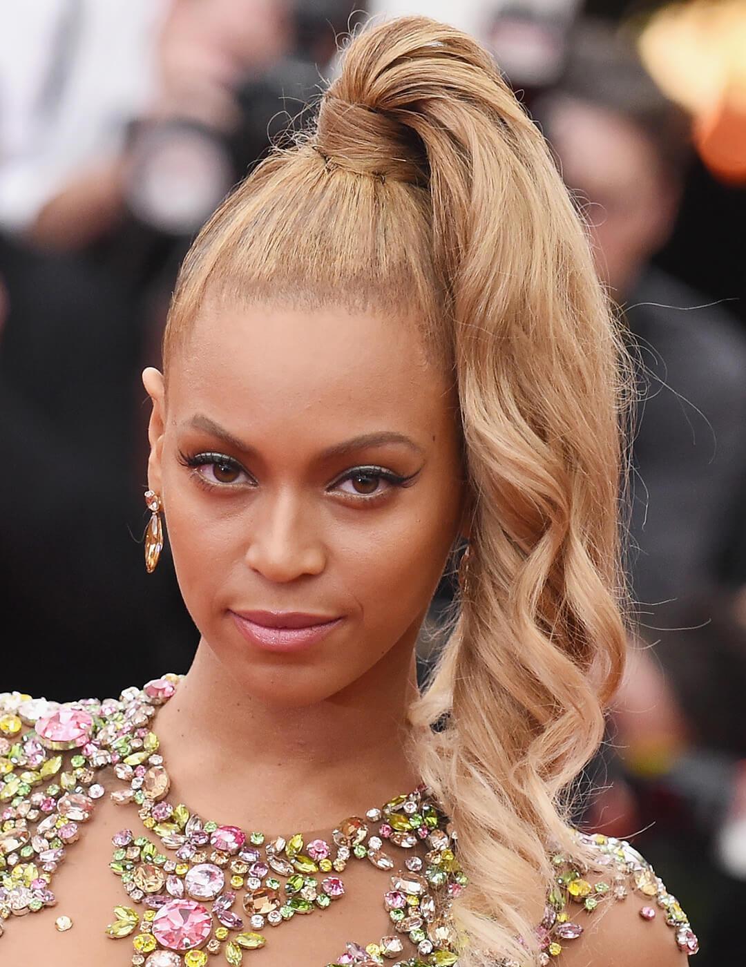 A close-up image of Beyonce wearing a dress accentuated with colorful beads with her hair on one side