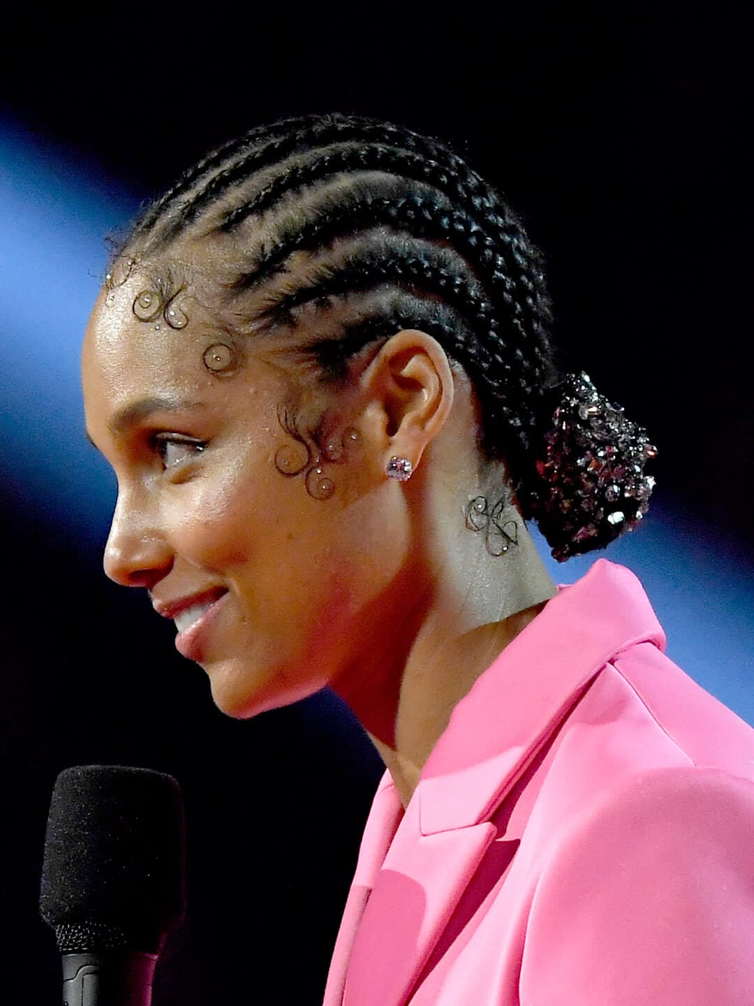 Side profile of Alicia Keys in a pink suit rocking a bejeweled, braided low bun hairstyle 