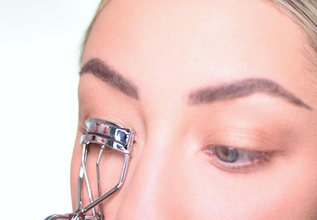 Close-up image of Anne Baker curling her lashes