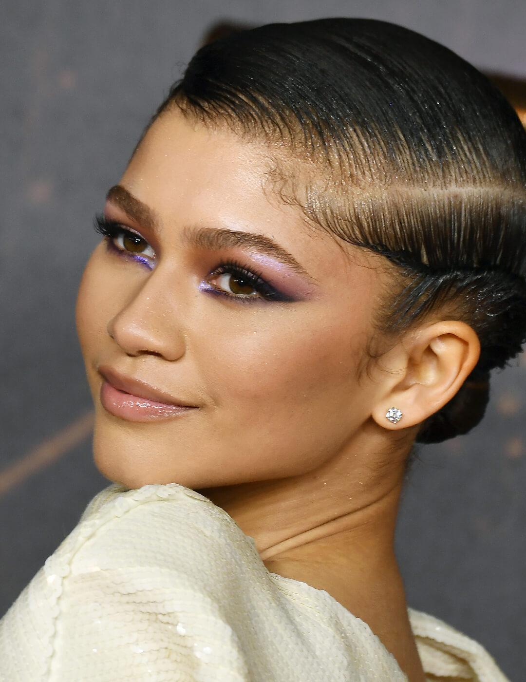 Zendaya rocking a bold periwinkle eye makeup look and white sequined dress