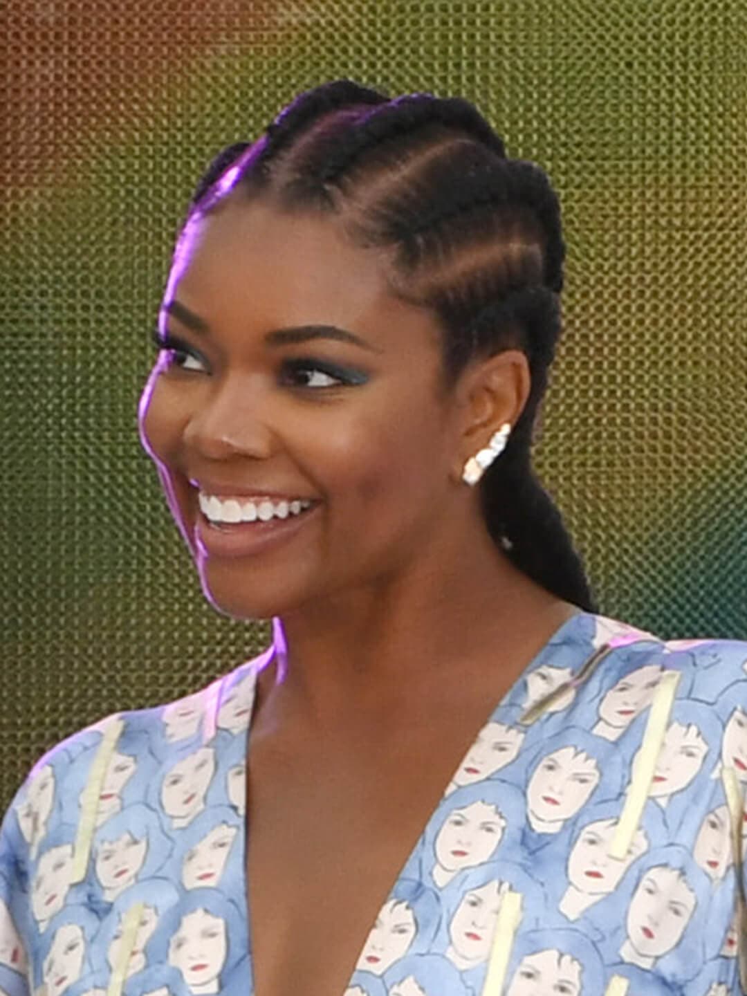Smiling Gabrielle Union rocking a braided pony tail hairstyle and graphic pattern dress