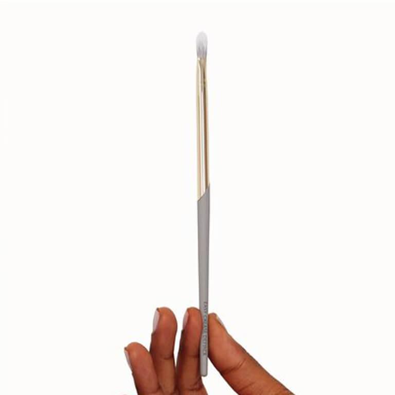 An image of a COMPLEX CULTURE eye makeup brush held upright by two fingers