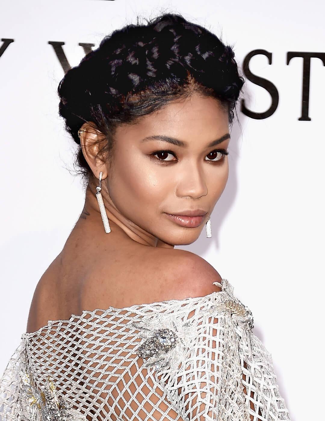 Close-up of Chanel Iman rocking a sultry makeup look, crown braids hairstyle, and a metallic fishnet dress embellished with rhinestones