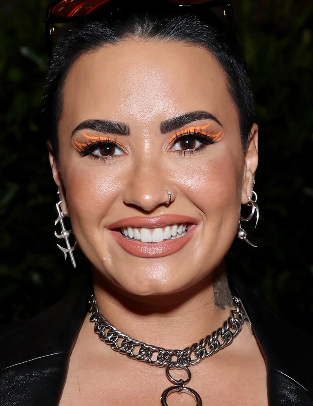 Demi Lovato rocking a neon orange graphic eyeliner makeup look