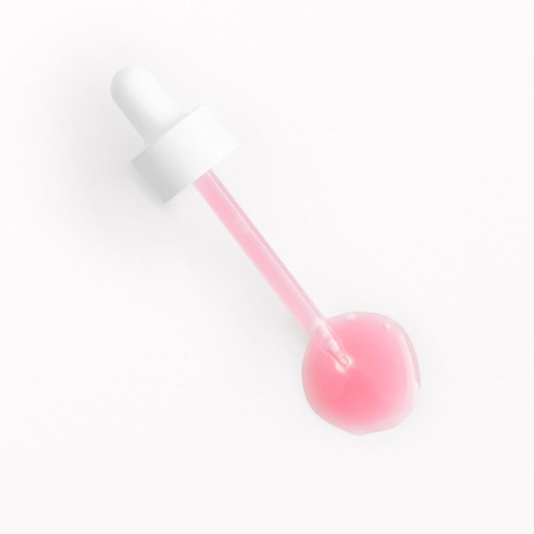 An image of a white dropper with pink liquid serum