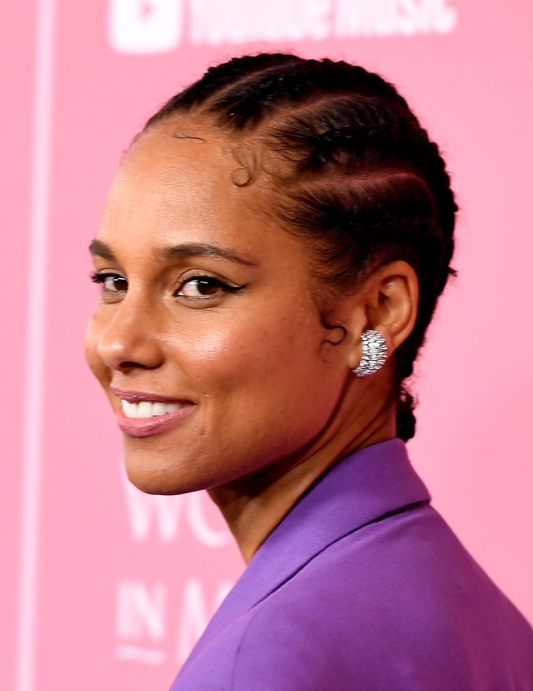 Alicia Keys looking chic in a purple suit, diamond-studded earrings, and cornrow braided hairstyle