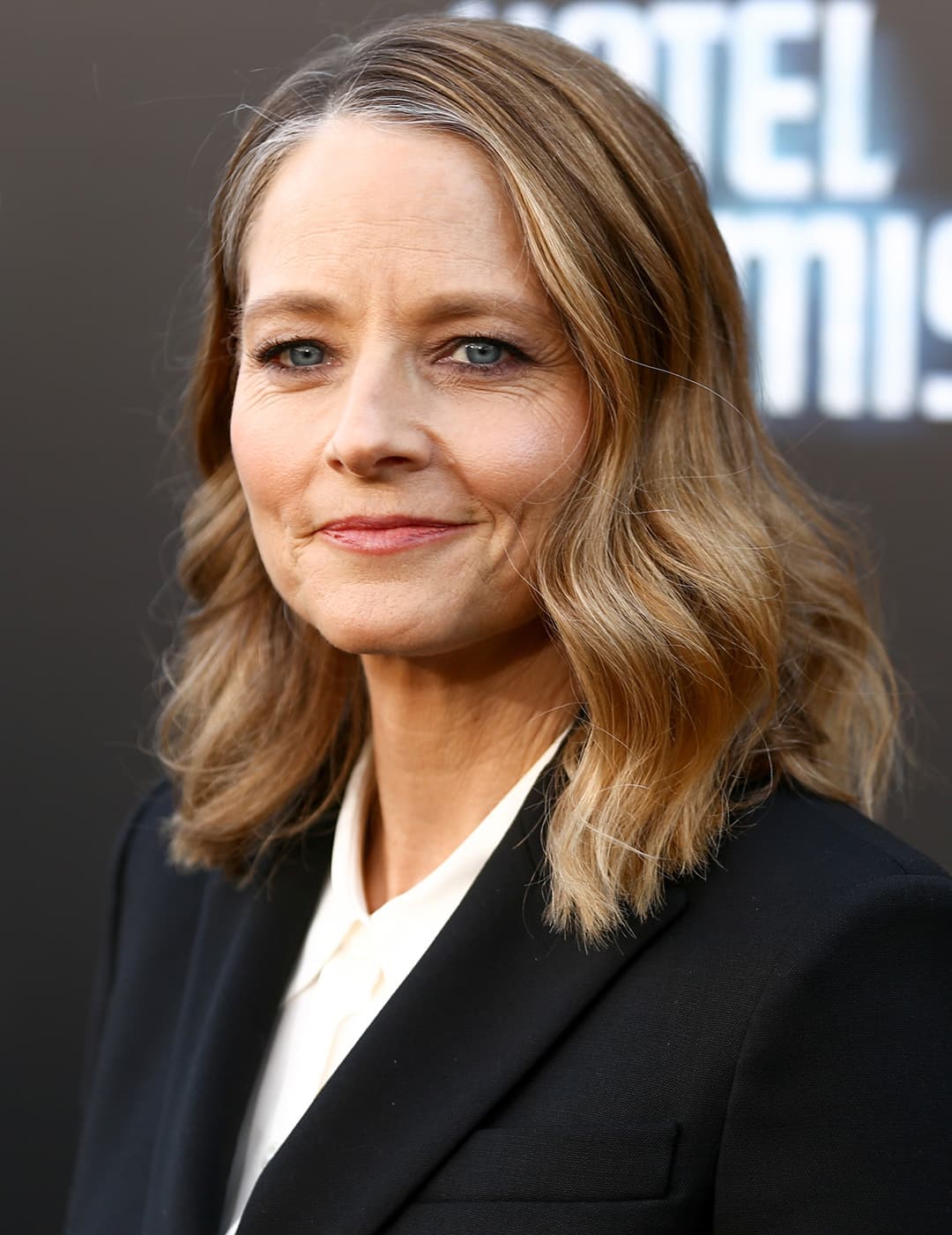 A photo of Jodie Foster wearing a simple black pantsuit with her tousled shoulder length hair