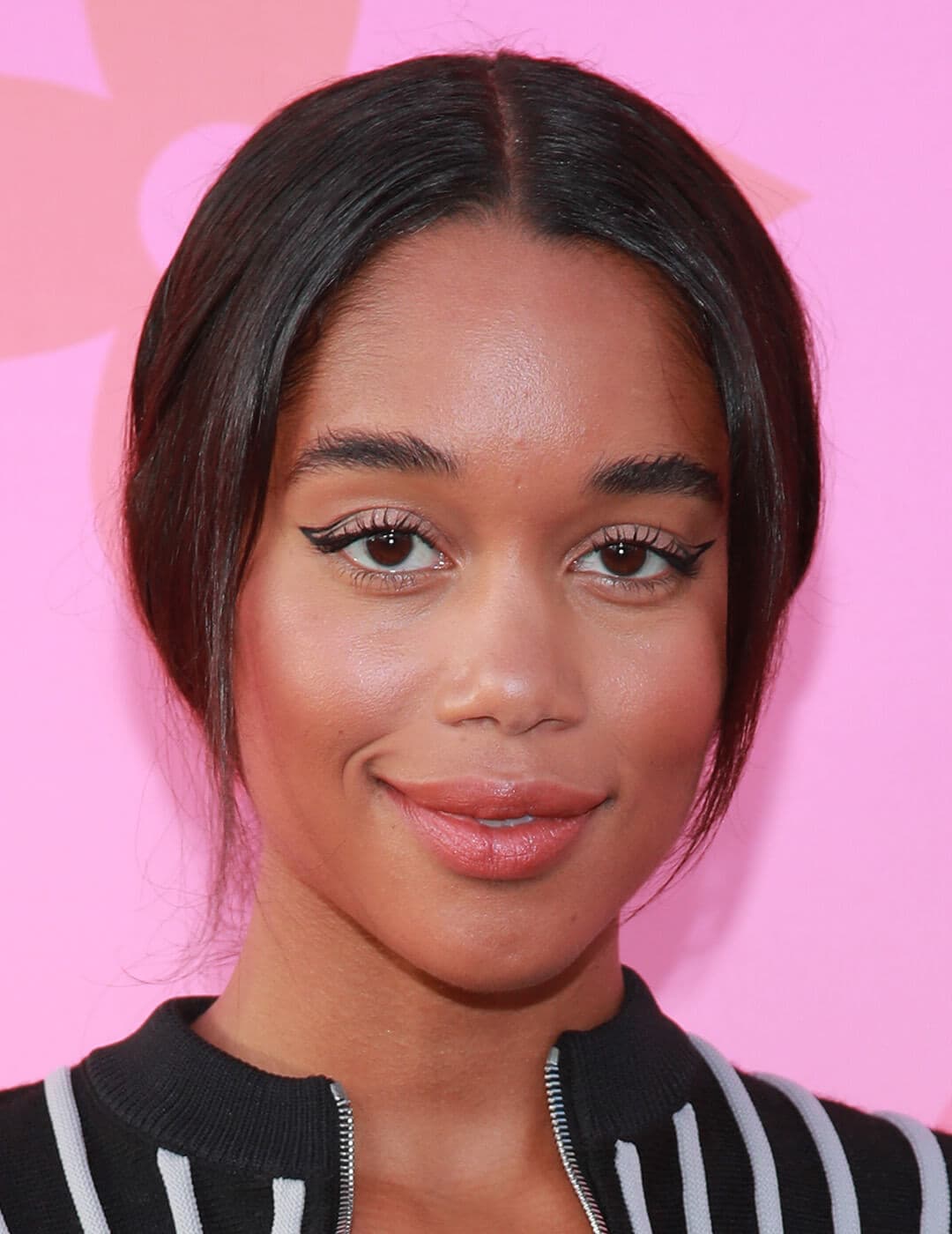 Close-up look of Laura Harrier rocking a minimal makeup look, low ponytail, wearing black and white striped top