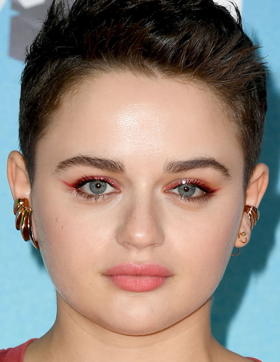 Close-up of Joey King with a shimmery red eyeliner makeup look paired with baby pink lips