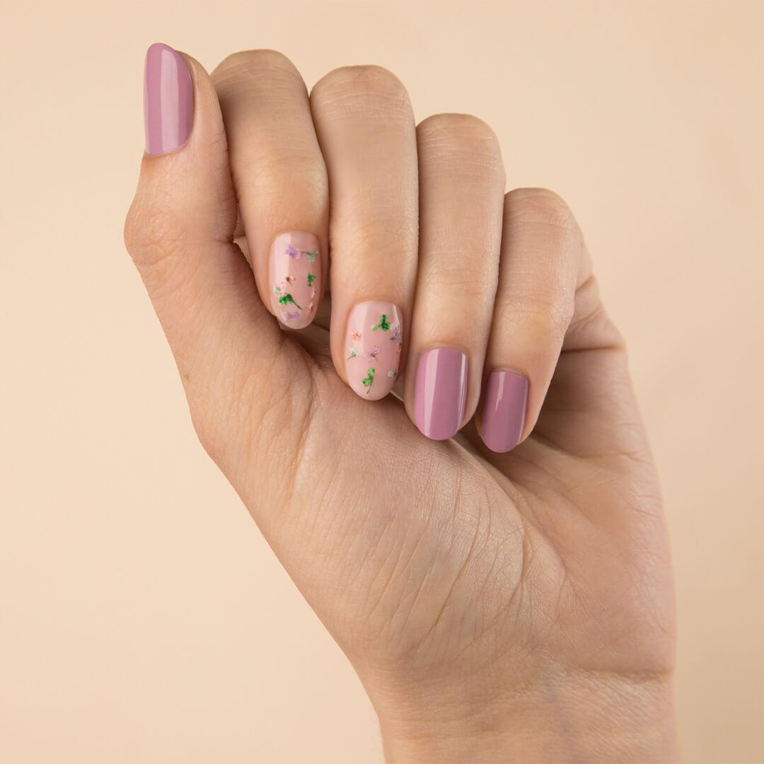 Close-up of a model's hand with mauve nail mani and dried flowers accent nail art