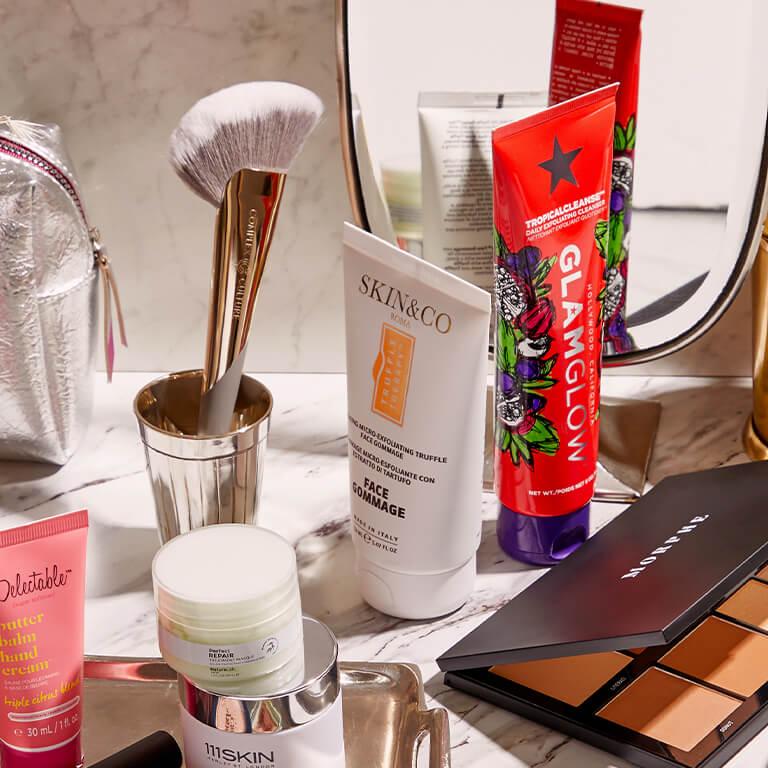 An image of skincare products, makeup products, and makeup tools on a marble surface