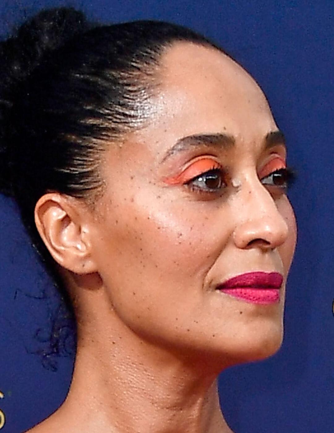 A photo of Tracee Ellis Ross with a neon orange eyeshadow and bold red lipstick